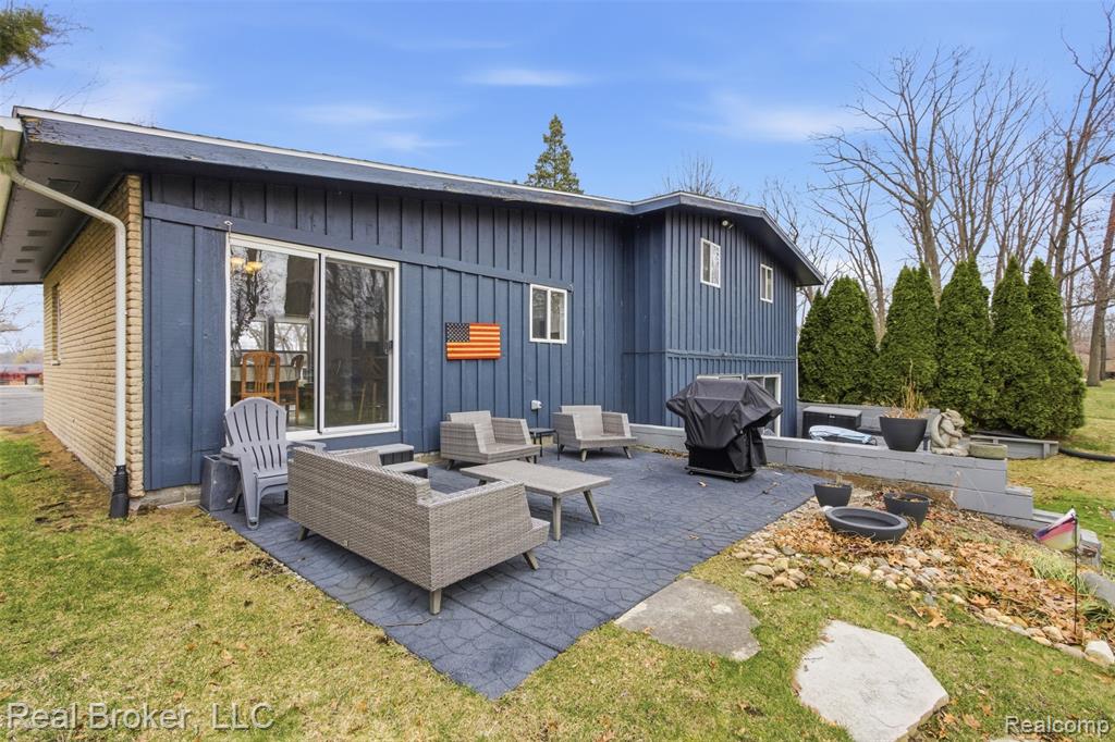 Back of property with an outdoor living space, board and batten siding, a patio area, and a lawn