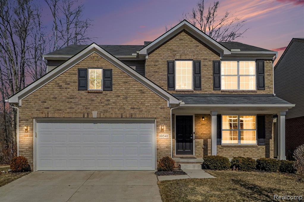 Traditional-style house with covered porch, driveway, and brick siding