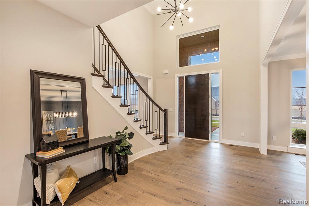 Foyer entrance with a chandelier, light wood-style flooring, a towering ceiling, and stairs