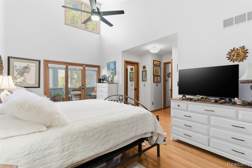 Bedroom with ceiling fan, access to outside, light wood finished floors, and a high ceiling