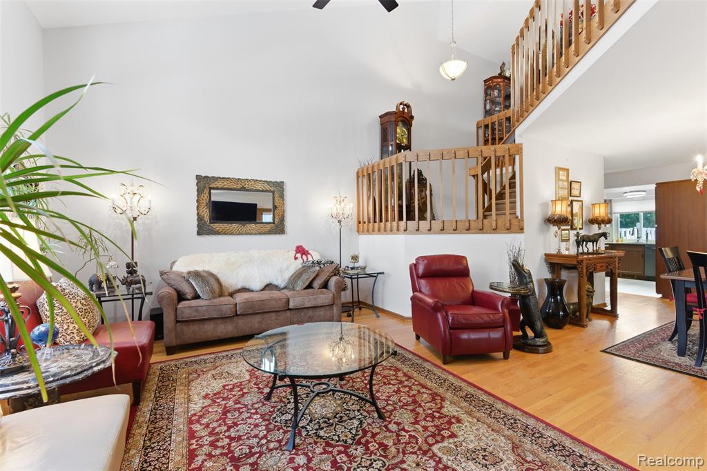 Living room featuring wood finished floors, ceiling fan, and lofted ceiling