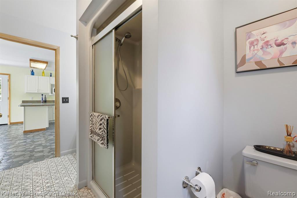 Bathroom featuring a shower stall with a frosted glass door, tiled flooring, and a commode