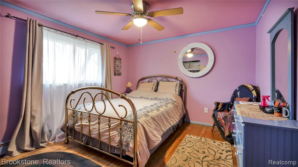 Bedroom featuring wood finished floors, a ceiling fan, and crown molding