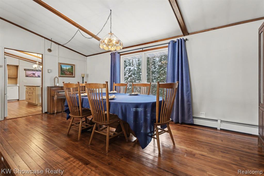 Dining area with dark wood-type flooring, lofted ceiling, baseboard heating, and hanging lights