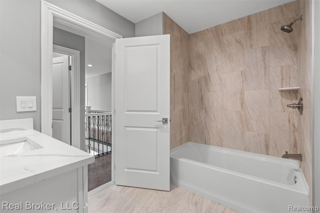 Full bathroom with shower / tub combination, double vanity, and light marble finish floors