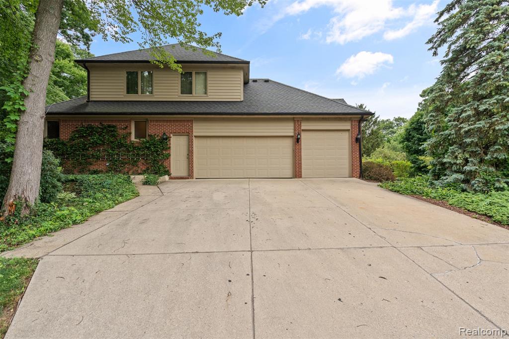 Traditional-style house with brick siding, concrete driveway, an attached garage, and a shingled roof