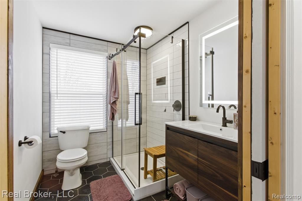 Bathroom featuring vanity, a shower stall, and dark tile patterned floors