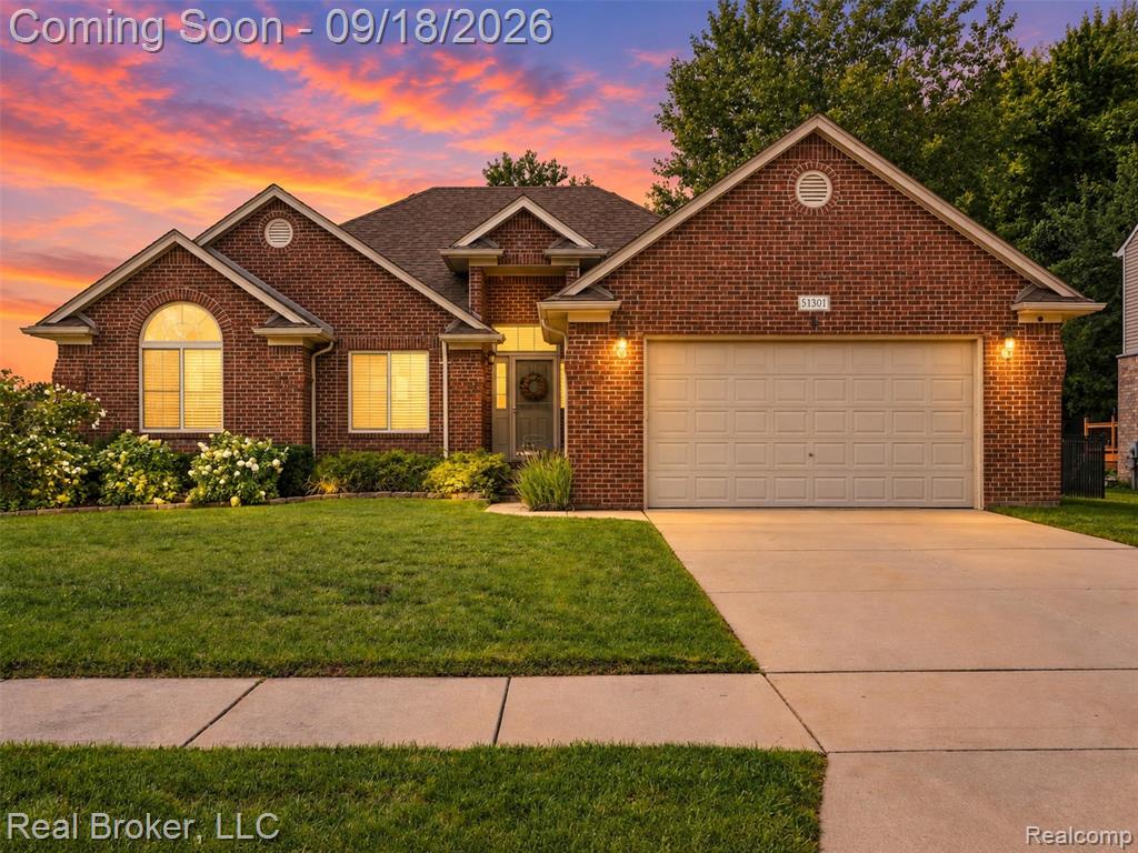 Brick exterior with gabled roof lines, attached two-car garage, concrete driveway, and front landscaping
