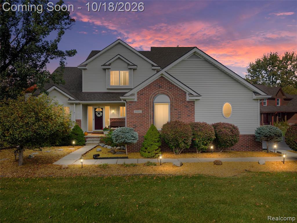 Two-story exterior featuring a brick and horizontal siding facade, arched window detailing, an oval accent window, and a paved front walkway