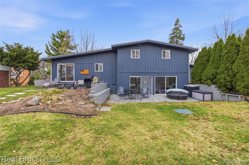 Rear view of property featuring a patio area, a hot tub, and a yard