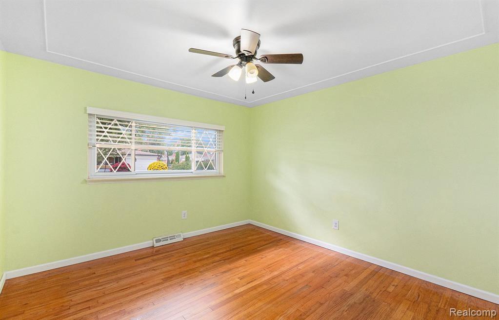 Empty room with hardwood / wood-style flooring and ceiling fan