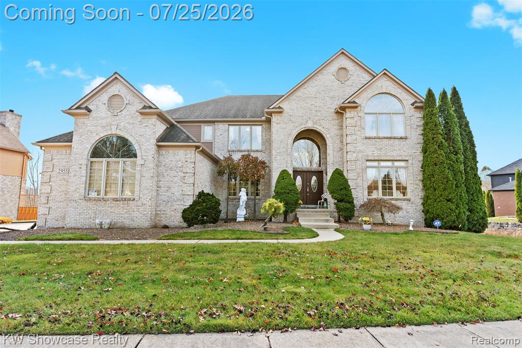 Stately brick exterior featuring an arched entryway, double front doors with decorative glass inserts, and multiple large windows