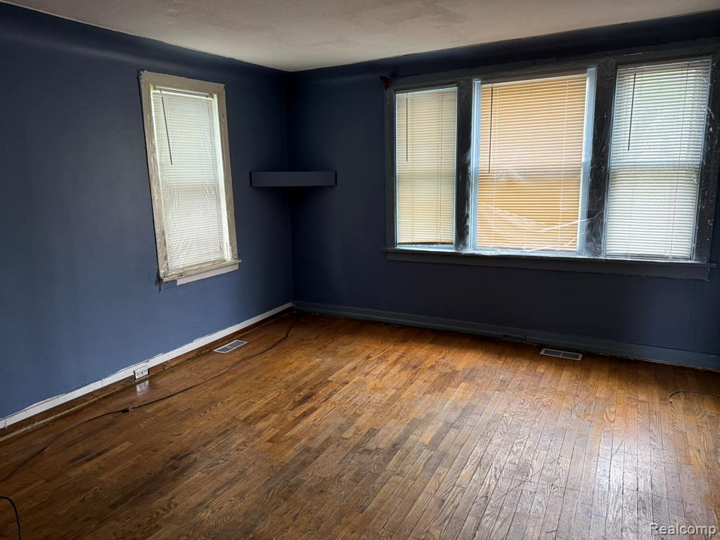 Empty room with dark wood finished floors and plenty of natural light