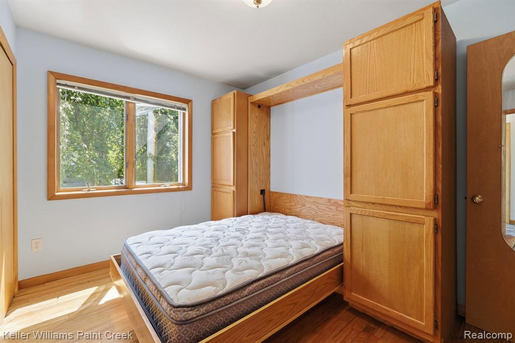 Hardwood flooring, natural wood window trim, built-in cabinetry, and a wall-mounted light fixture