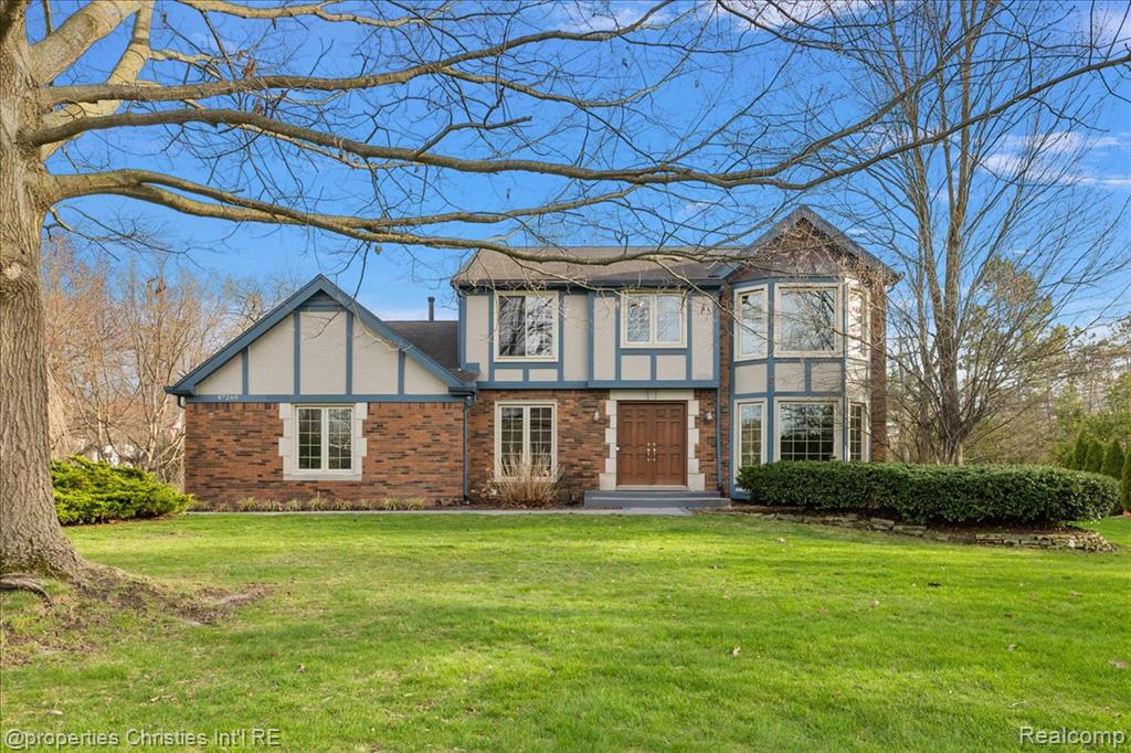 Tudor-style house featuring a front lawn, brick siding, and stucco siding
