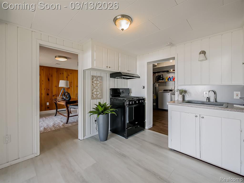 Kitchen with white cabinets, light wood-type flooring, and gas range