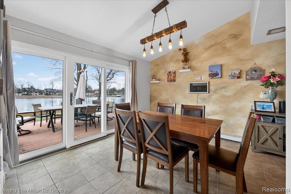 Dining room featuring lofted ceiling, a water view, light tile patterned floors, and baseboard heating