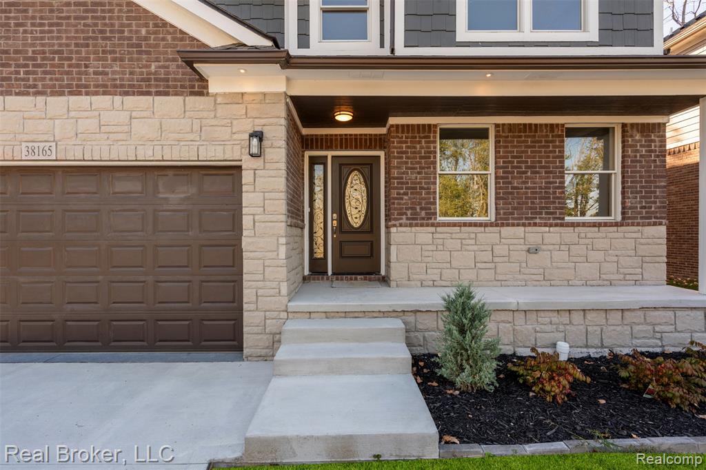 Property entrance with stone siding, driveway, and brick siding