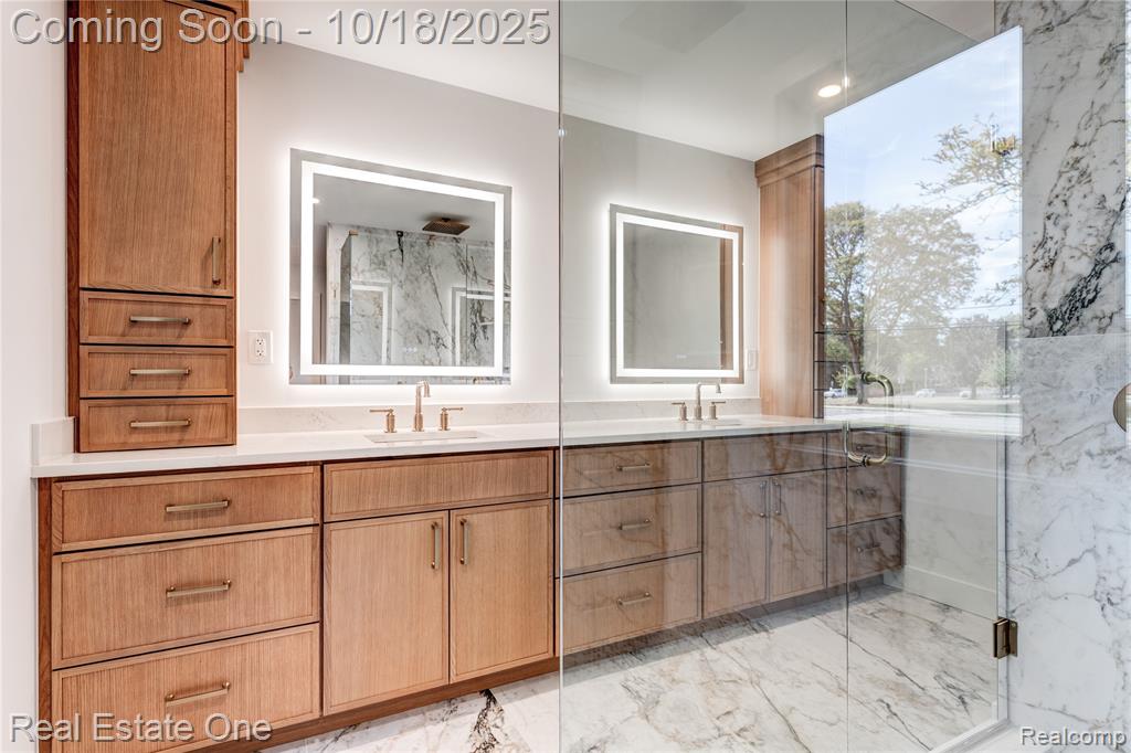 Bathroom with light marble finish flooring, double vanity, a marble finish shower, and recessed lighting