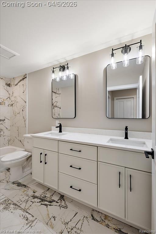 Full bath featuring double vanity and light marble finish flooring