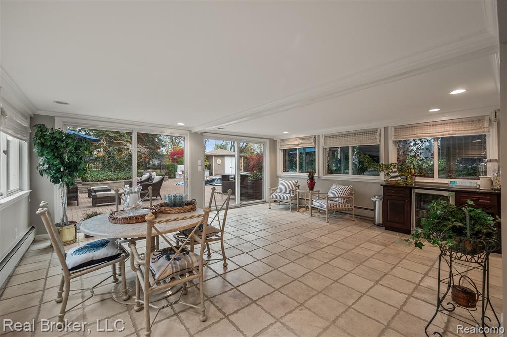Sunroom with beverage cooler, healthy amount of natural light, crown molding, a baseboard radiator, and recessed lighting