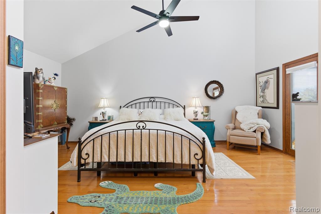 Bedroom with wood finished floors, ceiling fan, and vaulted ceiling