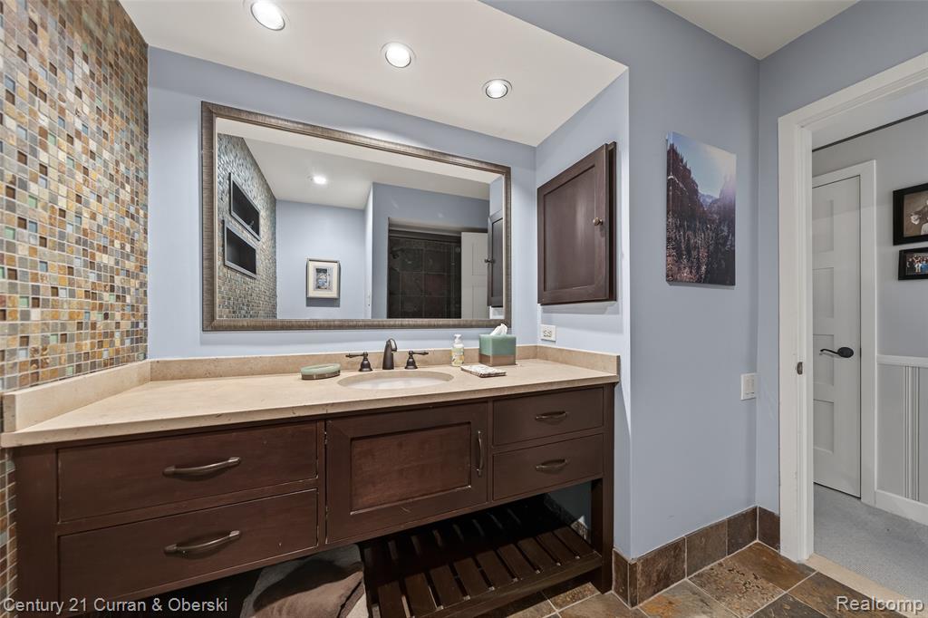 Full bathroom featuring stone tile floors, vanity, and a shower stall