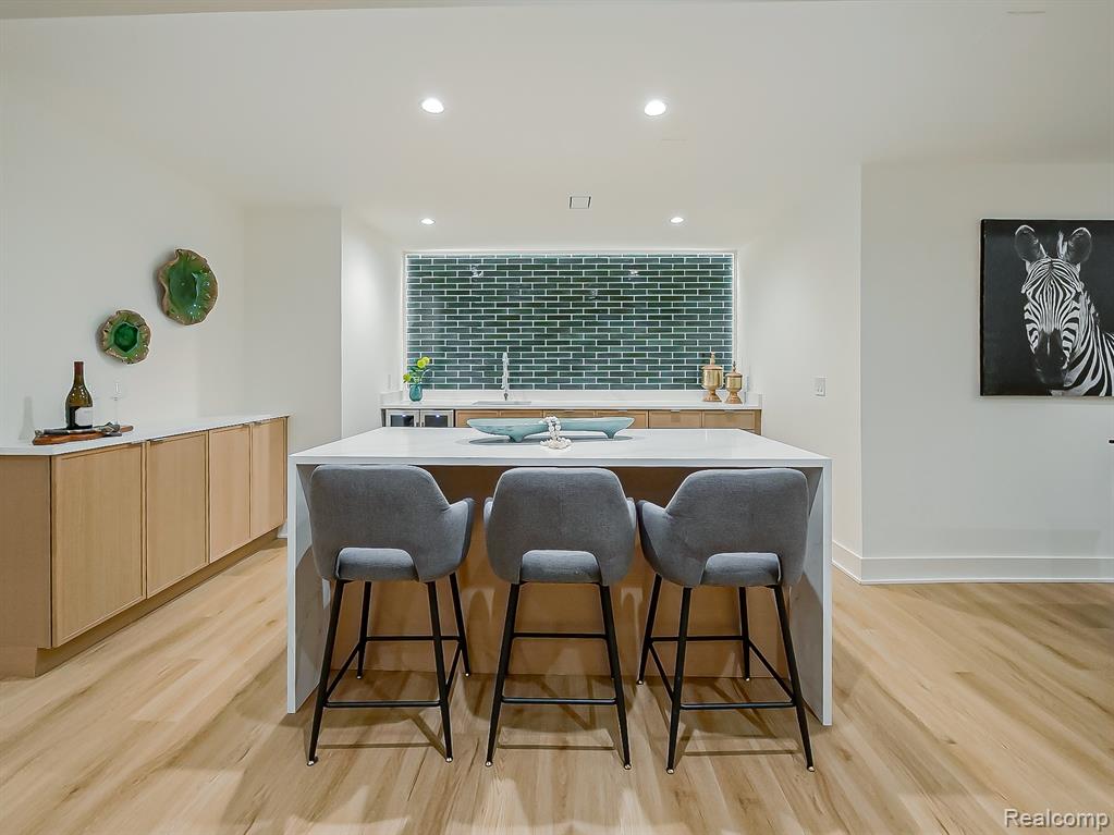 Kitchen with light brown cabinets, a kitchen breakfast bar, recessed lighting, light stone counters, and a center island