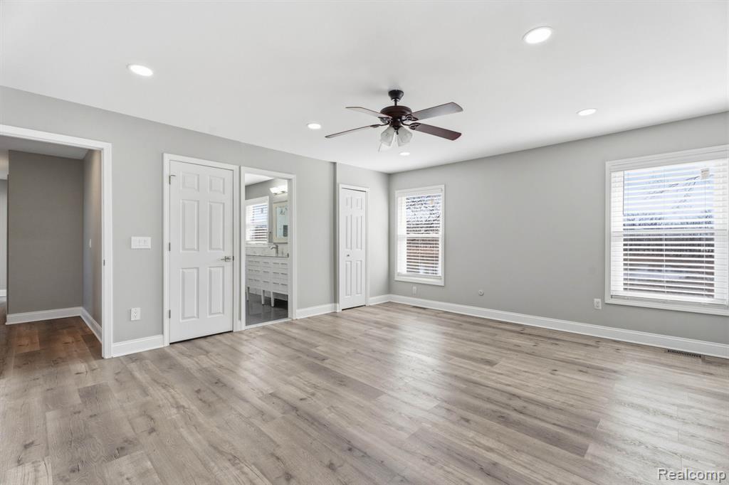 Unfurnished bedroom featuring ensuite bath, recessed lighting, multiple windows, a closet, and ceiling fan
