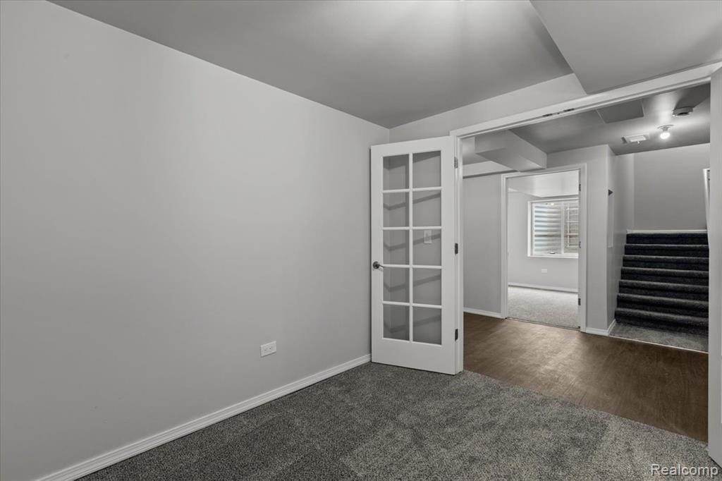 Snow covered rear of property featuring a garage and brick siding