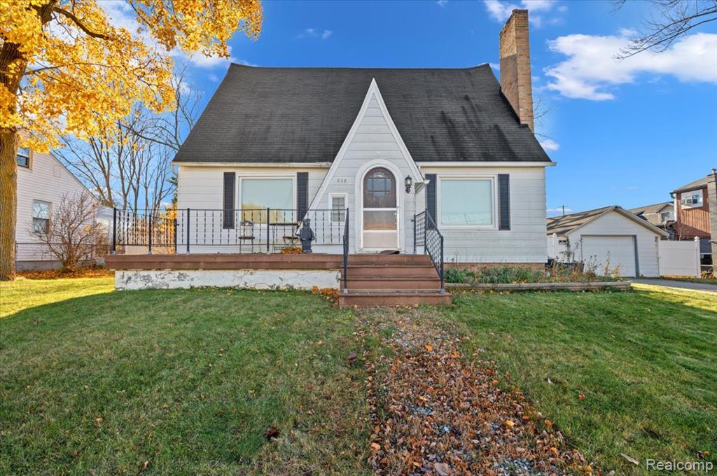 Photo for 238 E Nepessing Street, Lapeer, MI 48446 - listing #20251053765 View of front facade featuring a front yard, a chimney, an outdoor structure, a shingled roof, and a garage