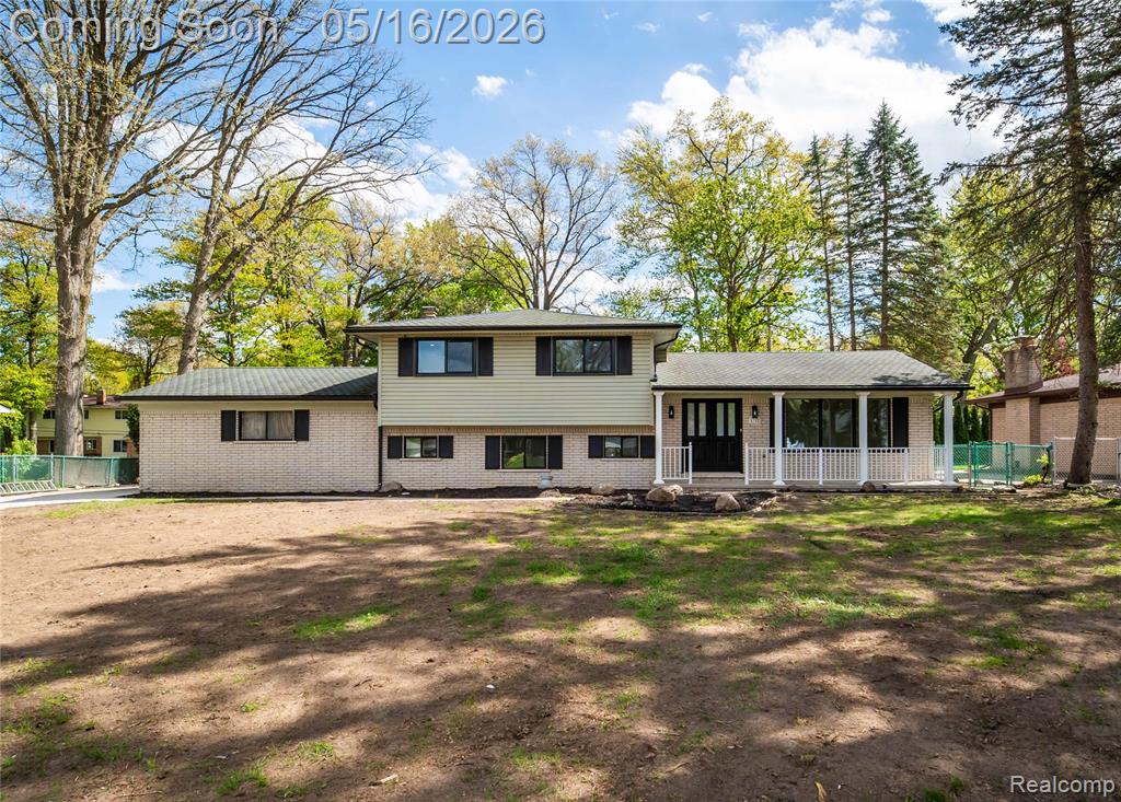 Split level home featuring brick siding and covered porch