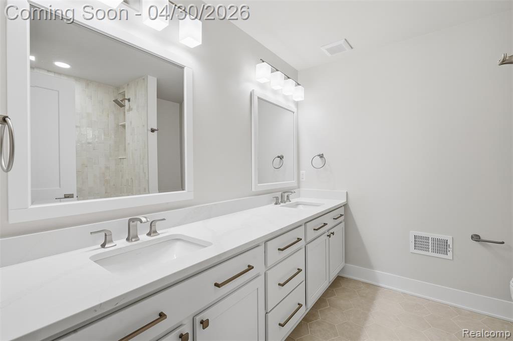 Full bath featuring double vanity, light tile patterned flooring, and tiled shower