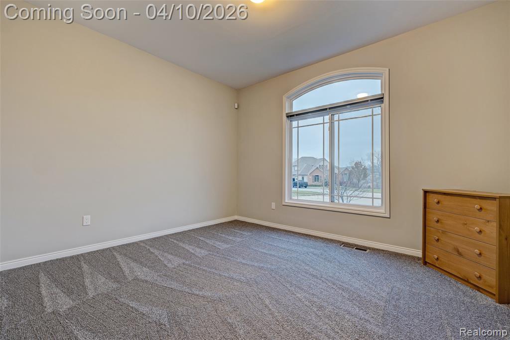 Carpeted spare room featuring baseboards