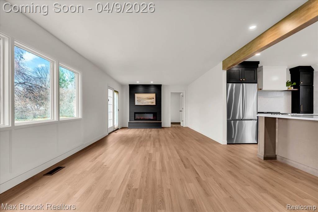 Unfurnished living room with light wood-style floors, a large fireplace, and recessed lighting