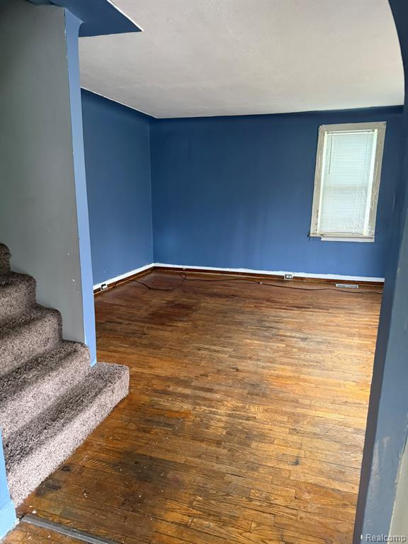 Empty room with dark wood-style flooring and stairway