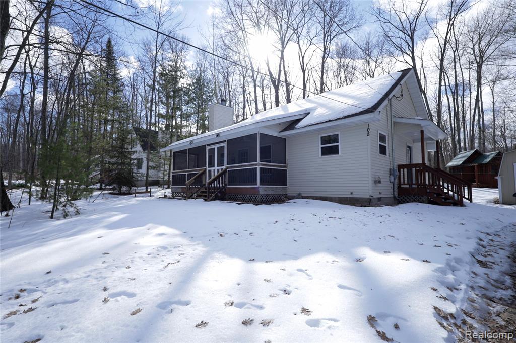 Snow covered property featuring a sunroom and a chimney