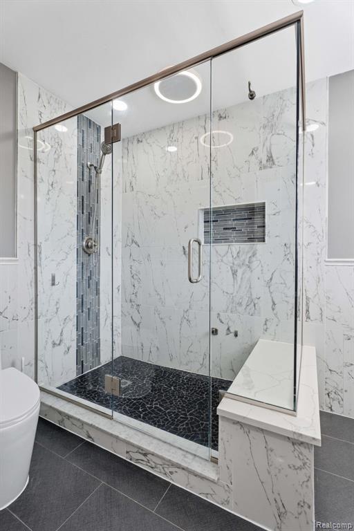Bathroom with tile walls and a marble finish shower