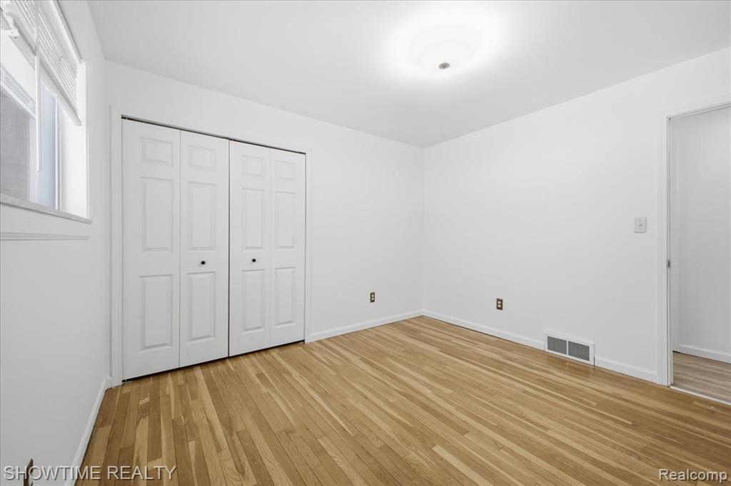 Unfurnished bedroom with light wood finished floors and a closet