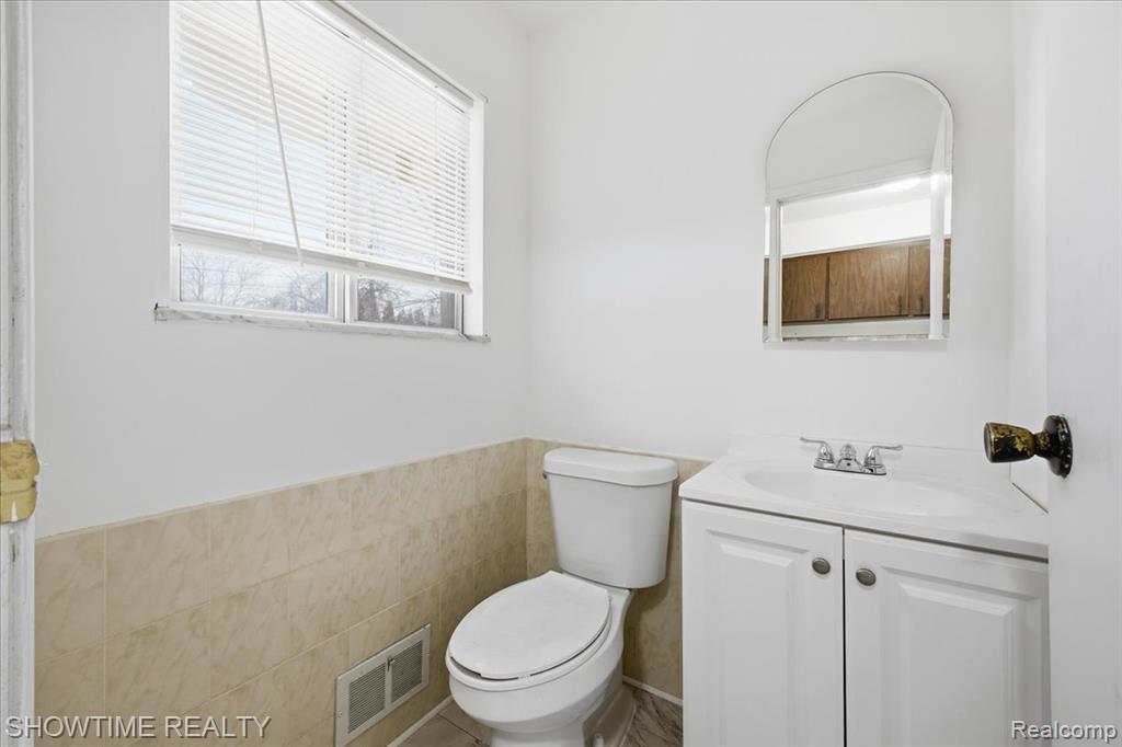 Bathroom featuring tile walls, vanity, and wainscoting