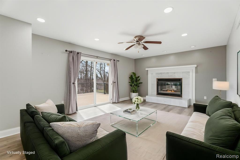 Living room featuring wood finished floors, ceiling fan, recessed lighting, and a tile fireplace