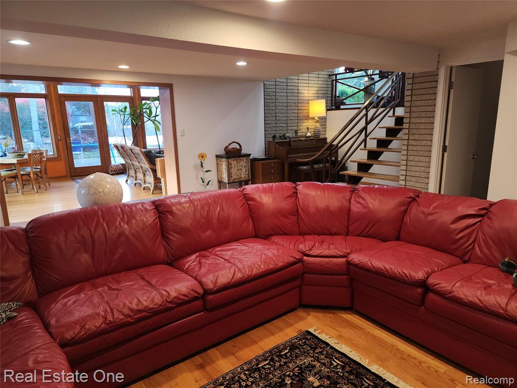 Living room with wood finished floors, a bar, plenty of natural light, recessed lighting, and stairway