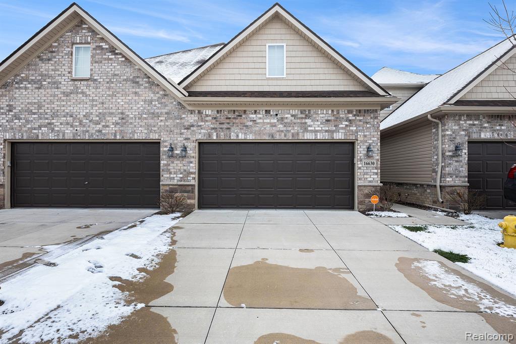 View of front of house featuring concrete driveway, a garage, brick siding, and stone siding