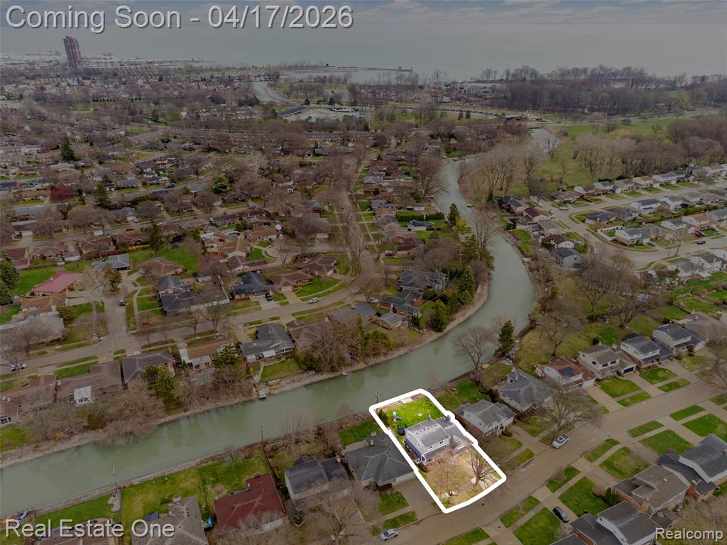 Aerial view of property and surrounding area featuring a large body of water, nearby suburban area, and property boundaries highlighted