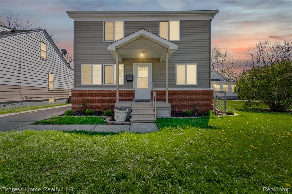 View of front facade featuring a lawn and brick siding