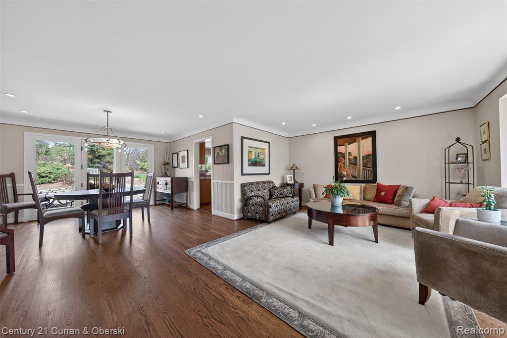 Living room featuring dark wood-type flooring, a chandelier, and crown molding