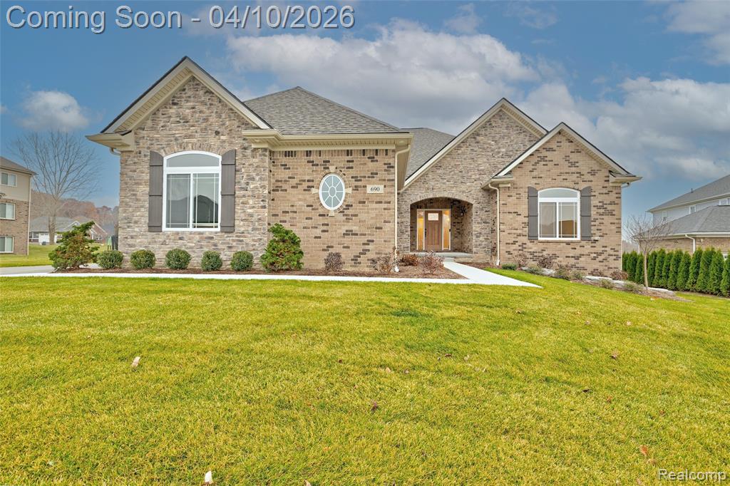 View of front of house featuring a front lawn, a shingled roof, and brick siding