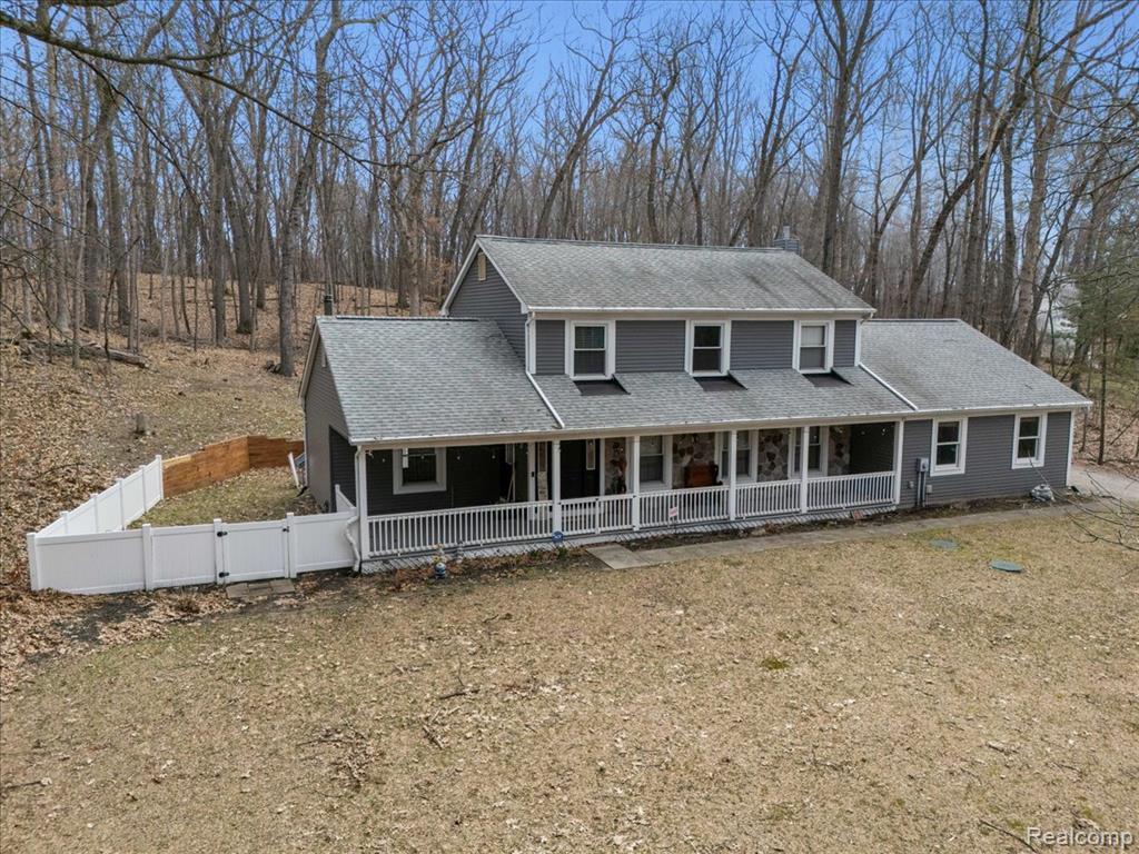 View of front of house featuring a porch, roof with shingles, and a gate