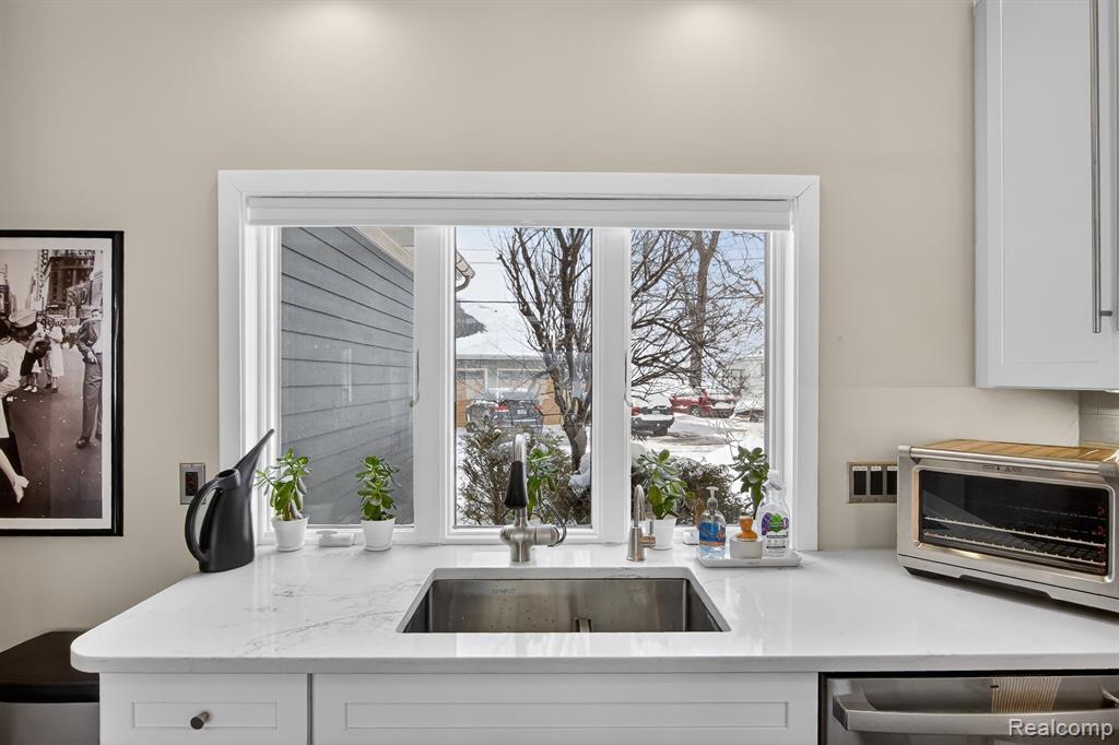 Kitchen with light stone countertops, white cabinetry, and stainless steel dishwasher