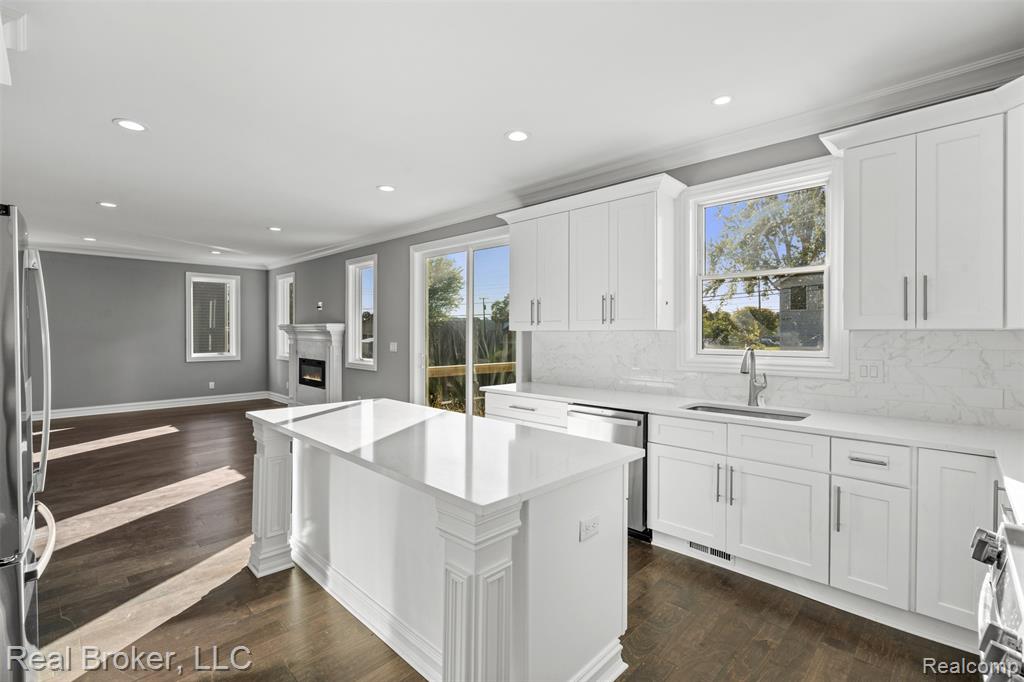 Kitchen featuring crown molding, recessed lighting, backsplash, white cabinetry, and dark wood-type flooring